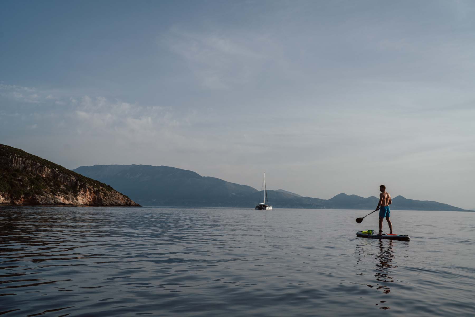 A paddleboarder on the sea with mountains in the background