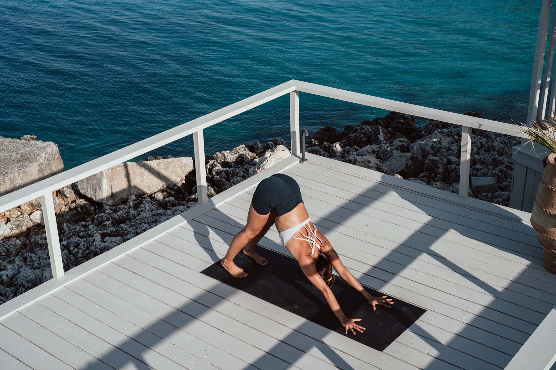 A girl doing yoga pose on a white deck overlooking the sea